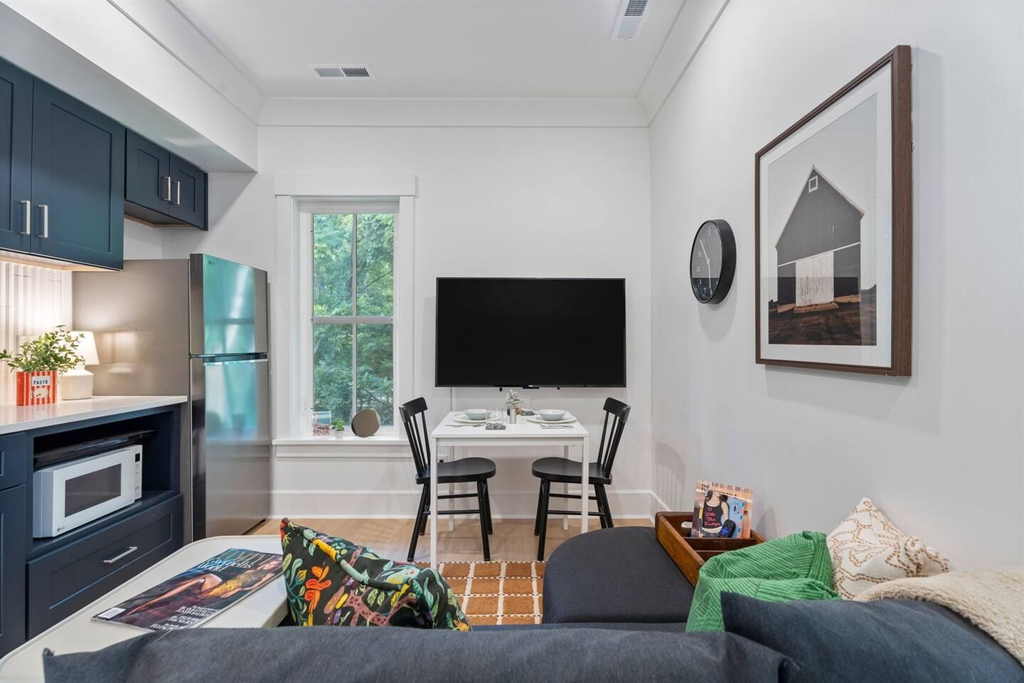 Een compacte leefruimte met een kitchenette, een eethoek met televisie en een bed.