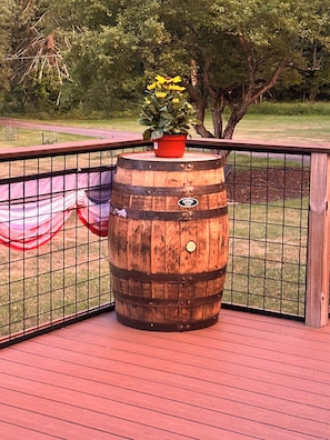 A wooden barrel with a potted plant on top, placed on a red deck with a metal railing. - Spacious 4 Bedroom tranquil & secluded family retreat! (Ellenville)
