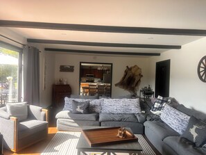 Uma sala de estar moderna com um sofá cinzento, uma mesa de centro de madeira e um tapete de pele grande.