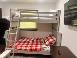 A bunk bed with a ladder, a desk with a remote control, and a window with blinds. - Spacious 4 Bedroom tranquil & secluded family retreat! (Ellenville)