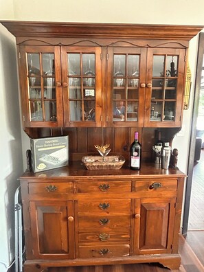 A wooden cabinet with glass doors, a box of a horse racing board game, a decorative glass dish, and a bottle of gin. - Spacious 4 Bedroom tranquil & secluded family retreat! (Ellenville)