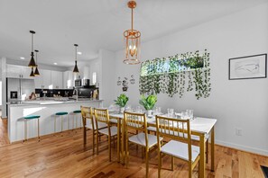 A modern kitchen with white cabinets, a central island, and pendant lighting. - Sky Deck - New Build - Downtown - Fenced - FirePit (Raleigh)