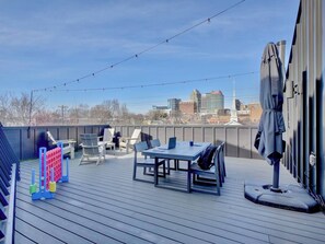 A rooftop deck with a table and chairs, a volleyball net, and a city skyline in the background. - 4 Ensuite Flats, Downtown, Architecture, Skyline (Raleigh)