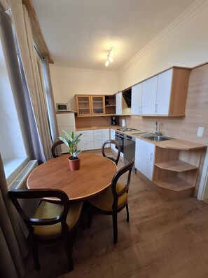 Eine kleine Küche mit Holzausstattung, einem Einbauofen und einer Essecke mit rundem Tisch und Stühlen.