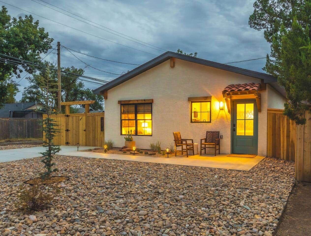 A single-story house with a front porch, two windows, and a door with a green door frame.