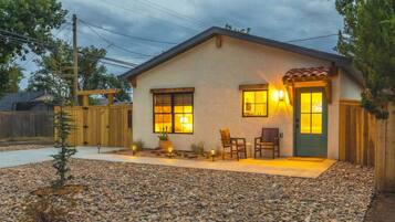 A single-story house with a front porch, two windows, and a door with a green door frame.