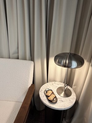 A hotel room with a bed, a round table with a marble top, and a modern floor lamp.