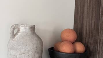 Un pichet en céramique grise et un bol noir contenant des oranges, le tout posé sur un comptoir gris.
