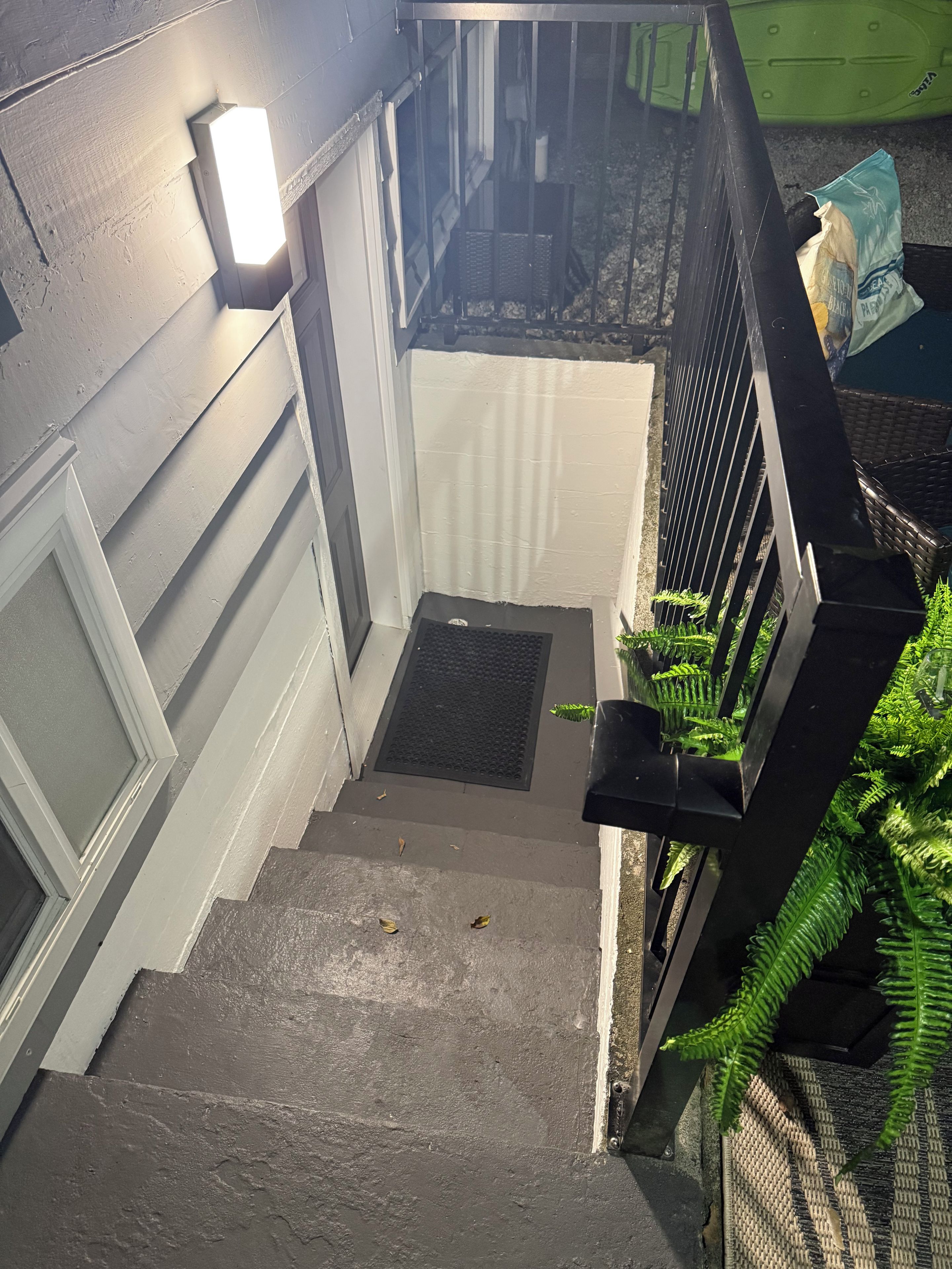 A staircase with a handrail, a light fixture, and a door with a window.