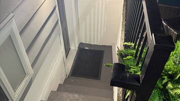A staircase with a handrail, a light fixture, and a door with a window.