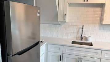 A kitchen with white cabinets, a stainless steel refrigerator, and a tiled backsplash.