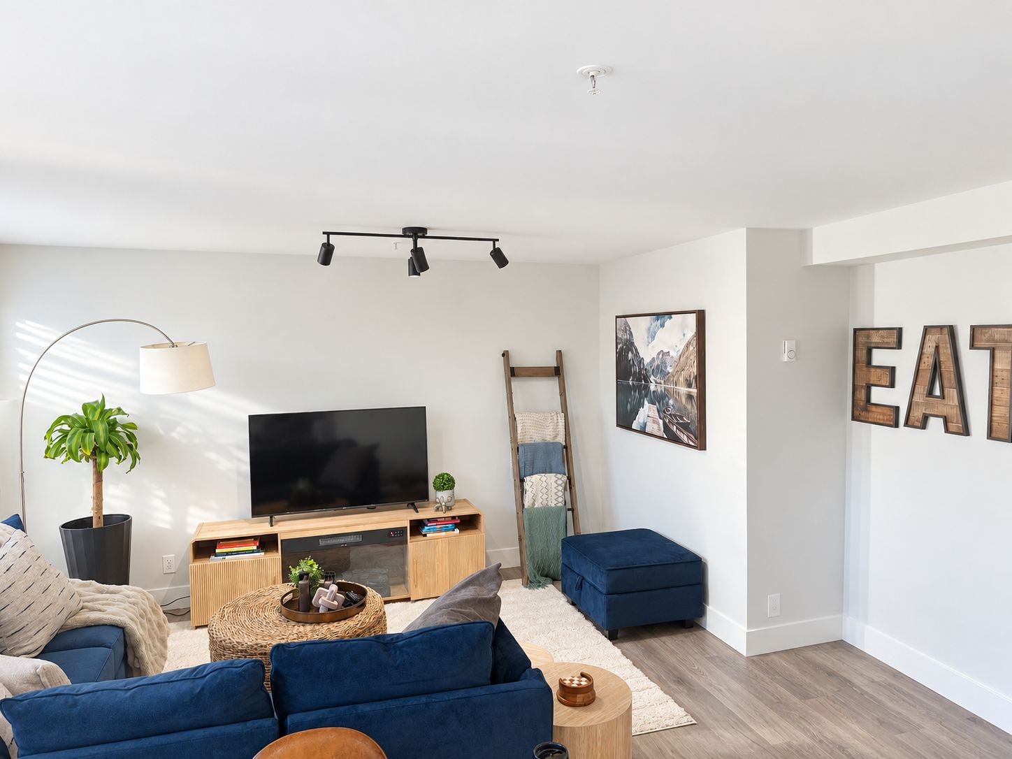 A modern living room with a flat-screen TV, a sofa, a coffee table, and a ladder against the wall.