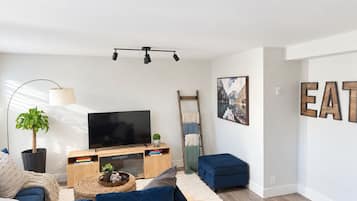 A modern living room with a flat-screen TV, a sofa, a coffee table, and a ladder against the wall.