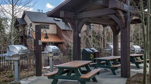 An outdoor patio area with picnic tables and barbecue grills. - Ski-In/Ski-Out Spacious 1BR Condo at Grand Timber Lodge, Sleeps 4 (Breckenridge)