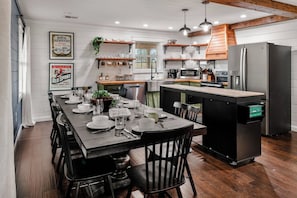 Una cocina moderna con una isla central, electrodomésticos de acero inoxidable y una zona de comedor preparada para seis personas.