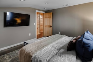 A bedroom with a bed, a television mounted on the wall, and a wooden closet. - Prather Ridge Estate | 3BR | Bourbon + Pickleball + Sauna (Chaplin)