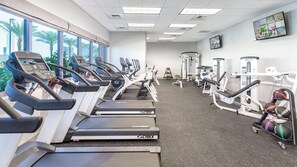 Une salle de sport équipée de tapis de course, d’appareils de musculation et de ballons d’exercice.