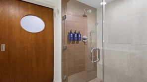 Ein Badezimmer mit einer Holztür, einer Duschkabine aus Glas und drei Toilettenartikeln an der Wand.