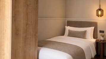 Una camera da letto moderna con un'armadio in legno, un letto con testiera, un comodino con lampada e una piccola pianta.