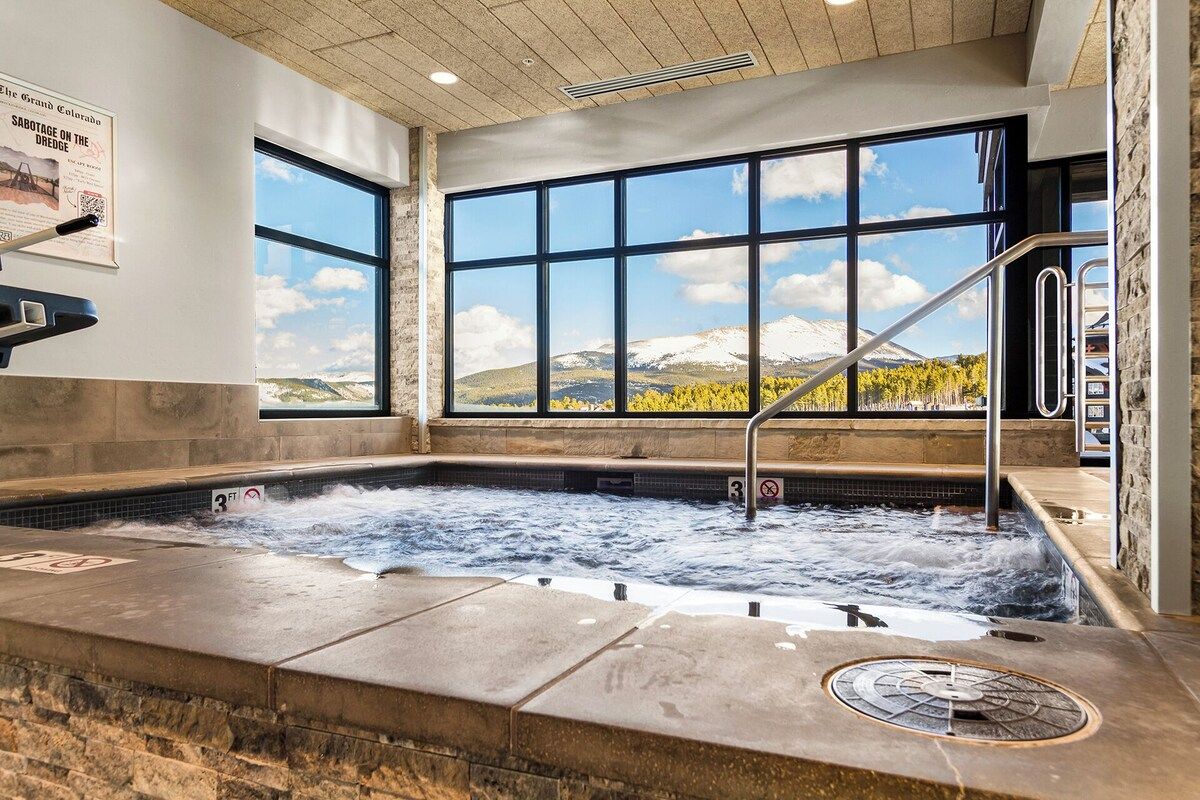 Un jacuzzi con vistas a montañas a través de amplios ventanales.