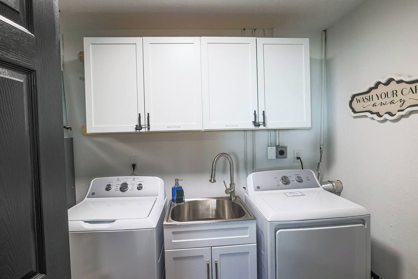A compact kitchen with two white appliances, a sink, and cabinets above.