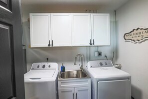 A compact kitchen with two white appliances, a sink, and cabinets above. - Stylish Cleveland Getaway Near Airport (Cleveland)