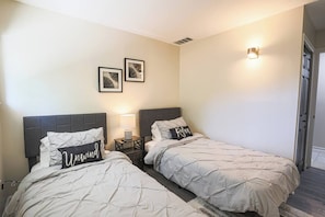 A hotel room with two beds, a nightstand with a lamp, and wall-mounted artwork. - Stylish Cleveland Getaway Near Airport (Cleveland)