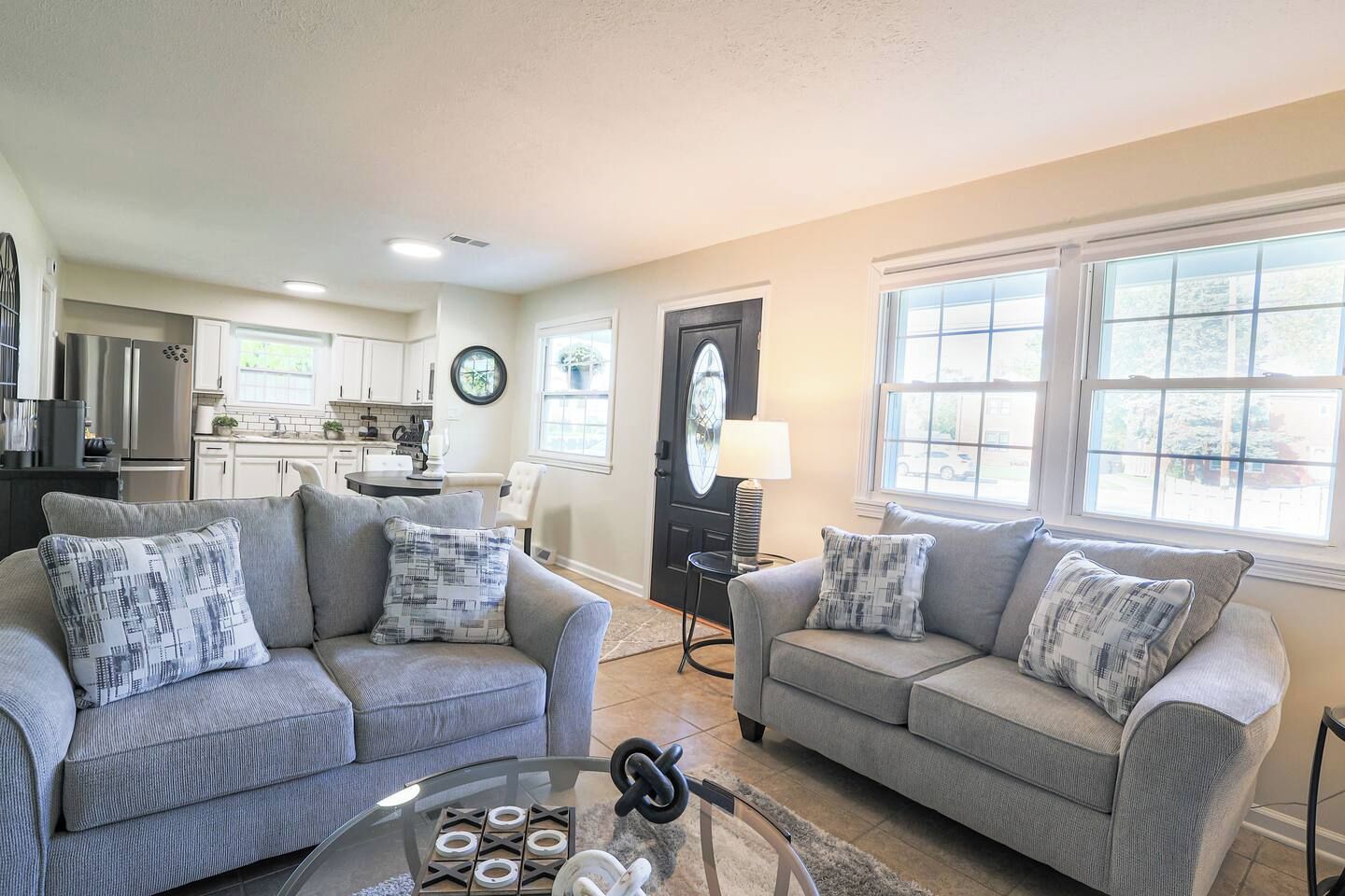 A living room with two grey sofas, a coffee table, and a kitchen in the background.