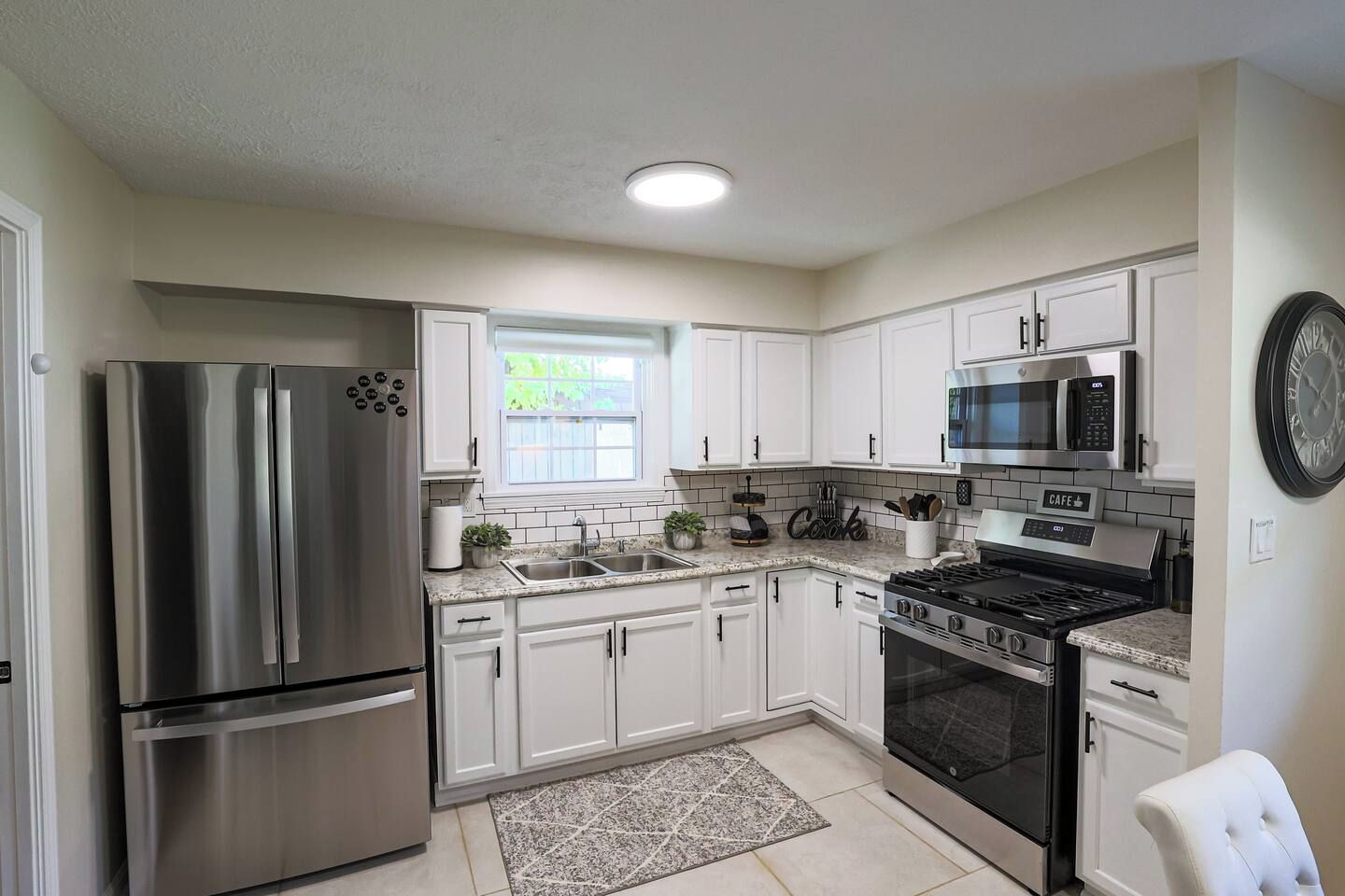 A modern kitchen with stainless steel appliances, white cabinetry, and a granite countertop.