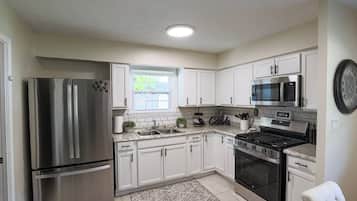 A modern kitchen with stainless steel appliances, white cabinetry, and a granite countertop.