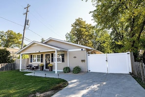 A single-story house with a covered porch, a fenced yard, and a driveway. - Stylish Cleveland Getaway Near Airport (Cleveland)