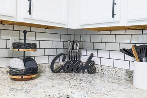 A kitchen with white cabinets, a tiled backsplash, and a 'Cook' sign. - Stylish Cleveland Getaway Near Airport (Cleveland)