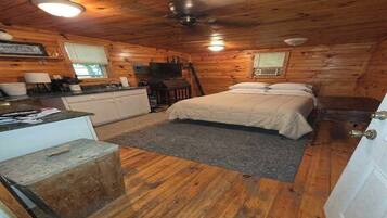 A cabin interior with a bed, kitchenette, and a ceiling fan.