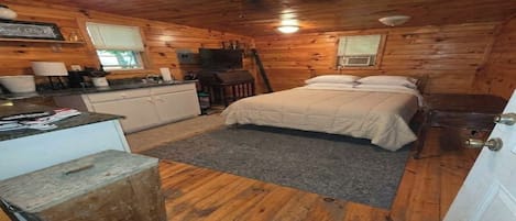 Interior de una cabaña con cama, kitchenette y ventilador de techo.