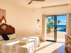 A bedroom with a bed, a ceiling fan, a view of the beach, and a pool. - Best Ocean View and Pool (San José del Cabo)