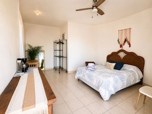 A bedroom with a bed, a desk, a coffee maker, a shelf, and a ceiling fan. - Best Ocean View and Pool (San José del Cabo)