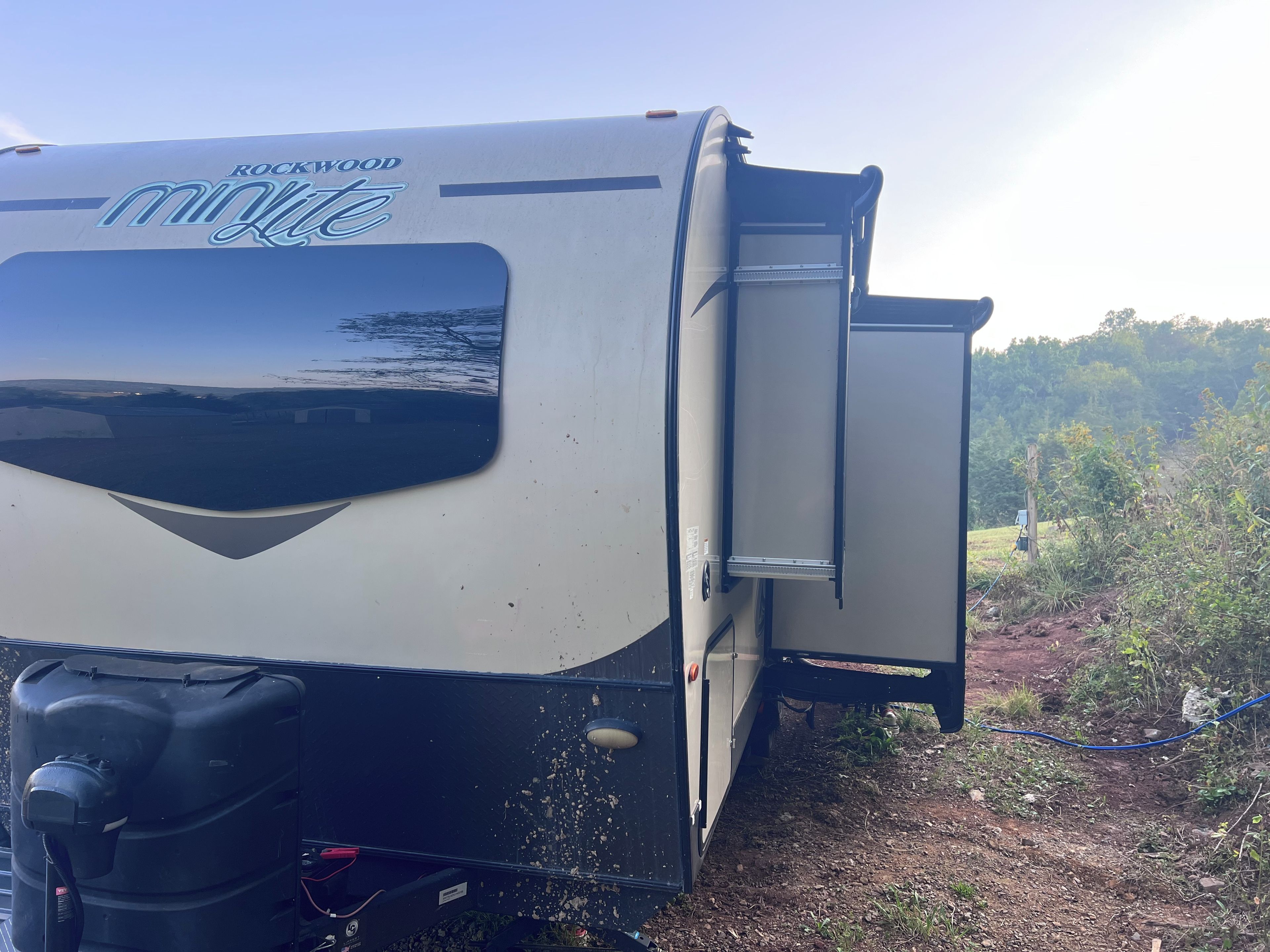 A recreational vehicle with a sliding door, a water tank, and a label reading 'ROCKWOOD minilite.'