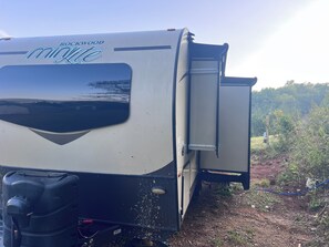 Un véhicule récréatif doté d’une porte coulissante, d’un réservoir d’eau et d’une étiquette indiquant « ROCKWOOD minilite ».