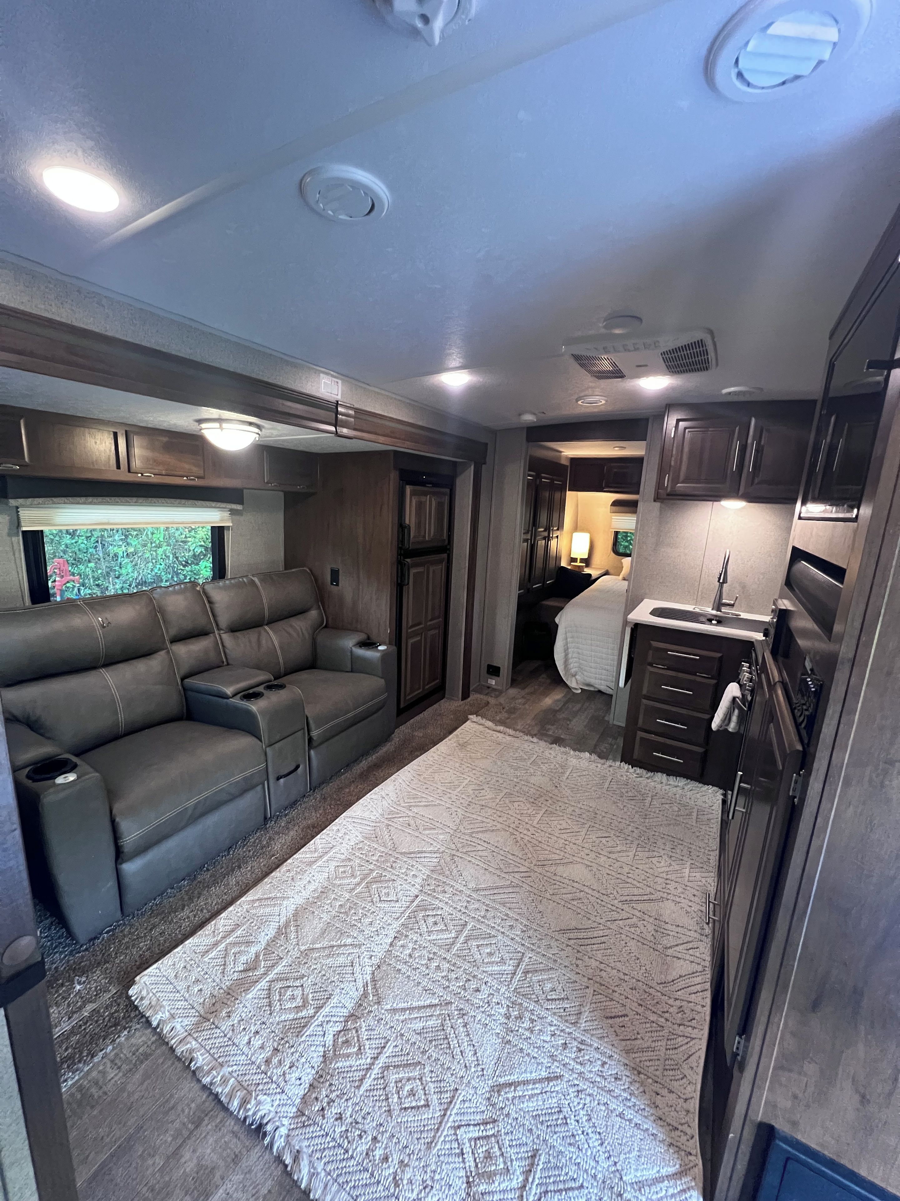 Interior compacto de autocaravana con sofá, kitchenette y ventana con vistas.