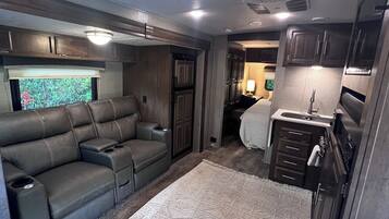 Interior compacto de autocaravana con sofá, kitchenette y ventana con vistas.