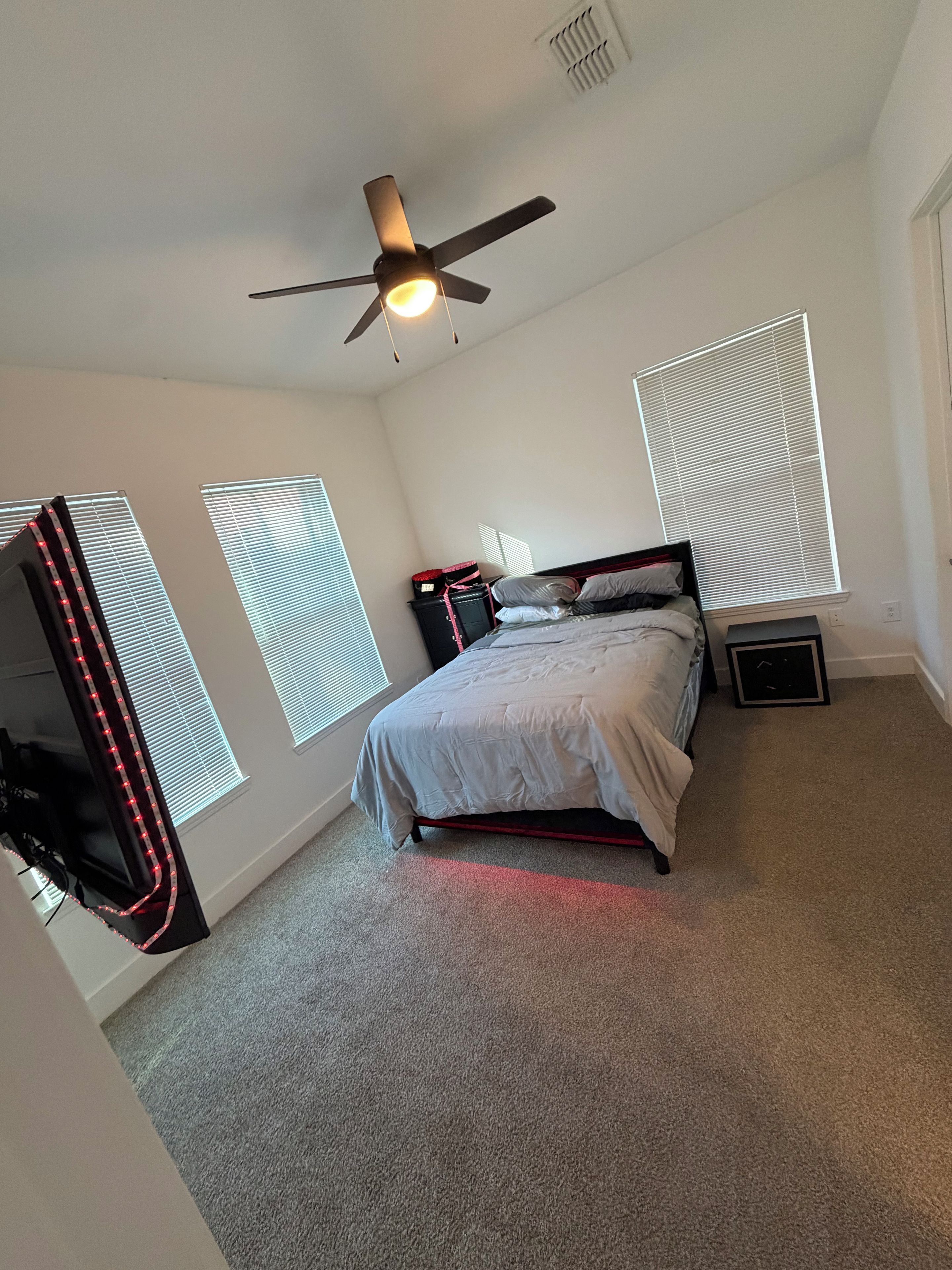 A bedroom with a bed, ceiling fan, and window blinds.