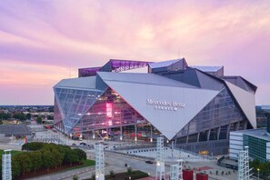 A modern stadium with a unique angular design, featuring a prominent Mercedes-Benz logo. - The Midnight Escape/Fast&Furious Suite (Atlanta)
