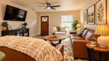 A living room with a sofa, coffee table, and a TV mounted on the wall.