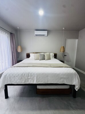 A bedroom with a bed, an air conditioning unit, and a window with curtains. - Premiun 1-Bed Apart in Pinilla - Tamarindo - Avellanas w AC / Pool / Rancho BBQ (Pinilla)