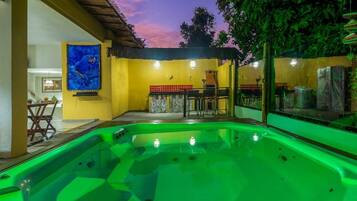 A swimming pool with a bar area, a dining table, and a mural on the wall.