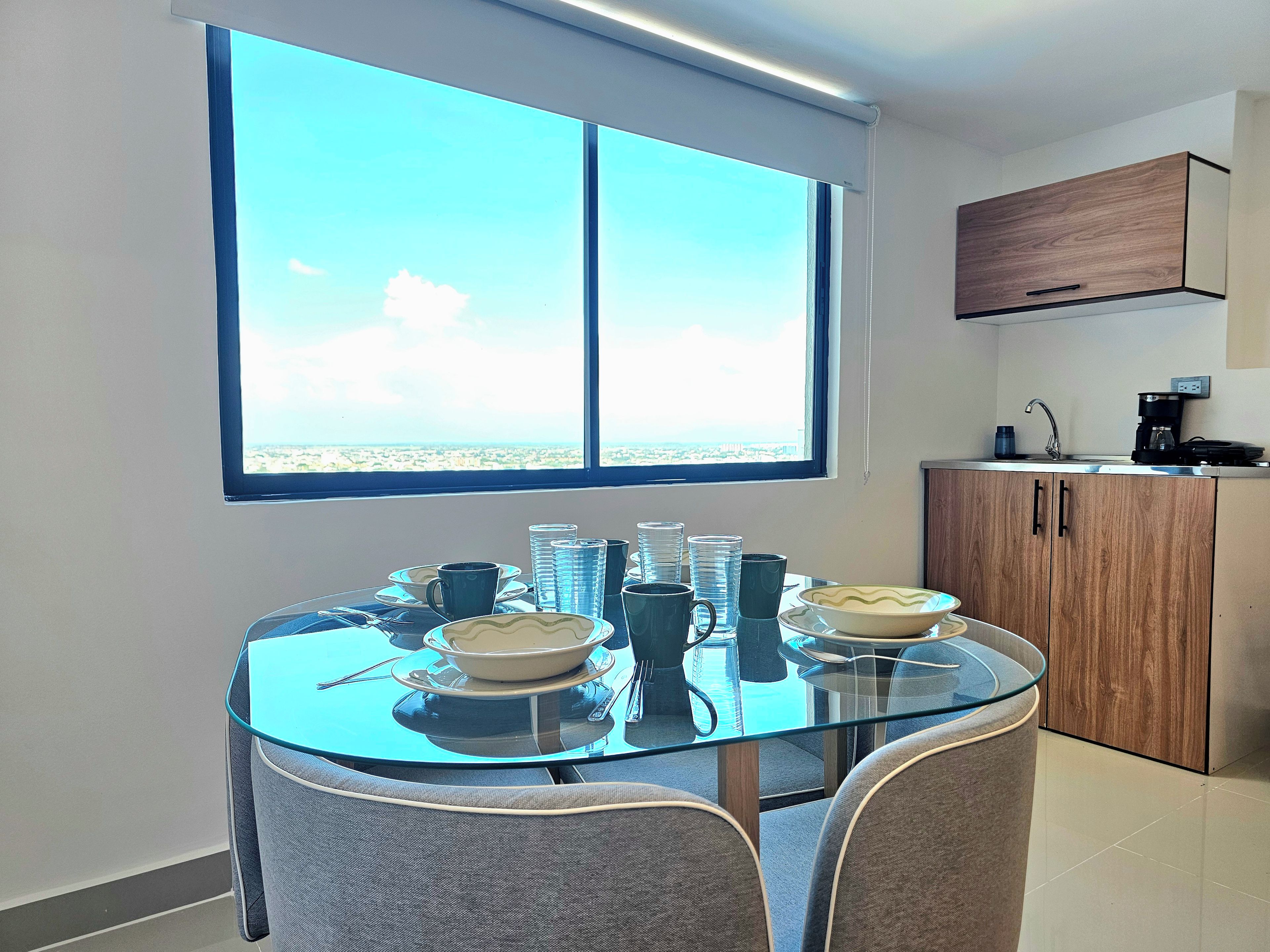 Una cocina moderna con un amplio ventanal, una mesa de comedor con sillas y una cafetera.