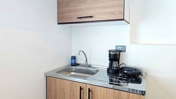 A compact kitchen with a sink, a coffee maker, and a stove.