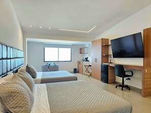 Un dormitorio moderno con dos camas, un escritorio, un televisor y una ventana.