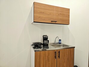 Una kitchenette compacta con estufa integrada, cafetera y lavamanos.