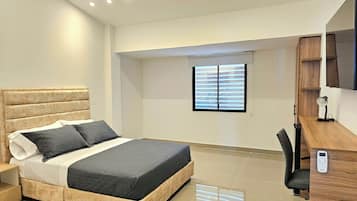Un dormitorio moderno con cama, mesita de noche y escritorio con silla.